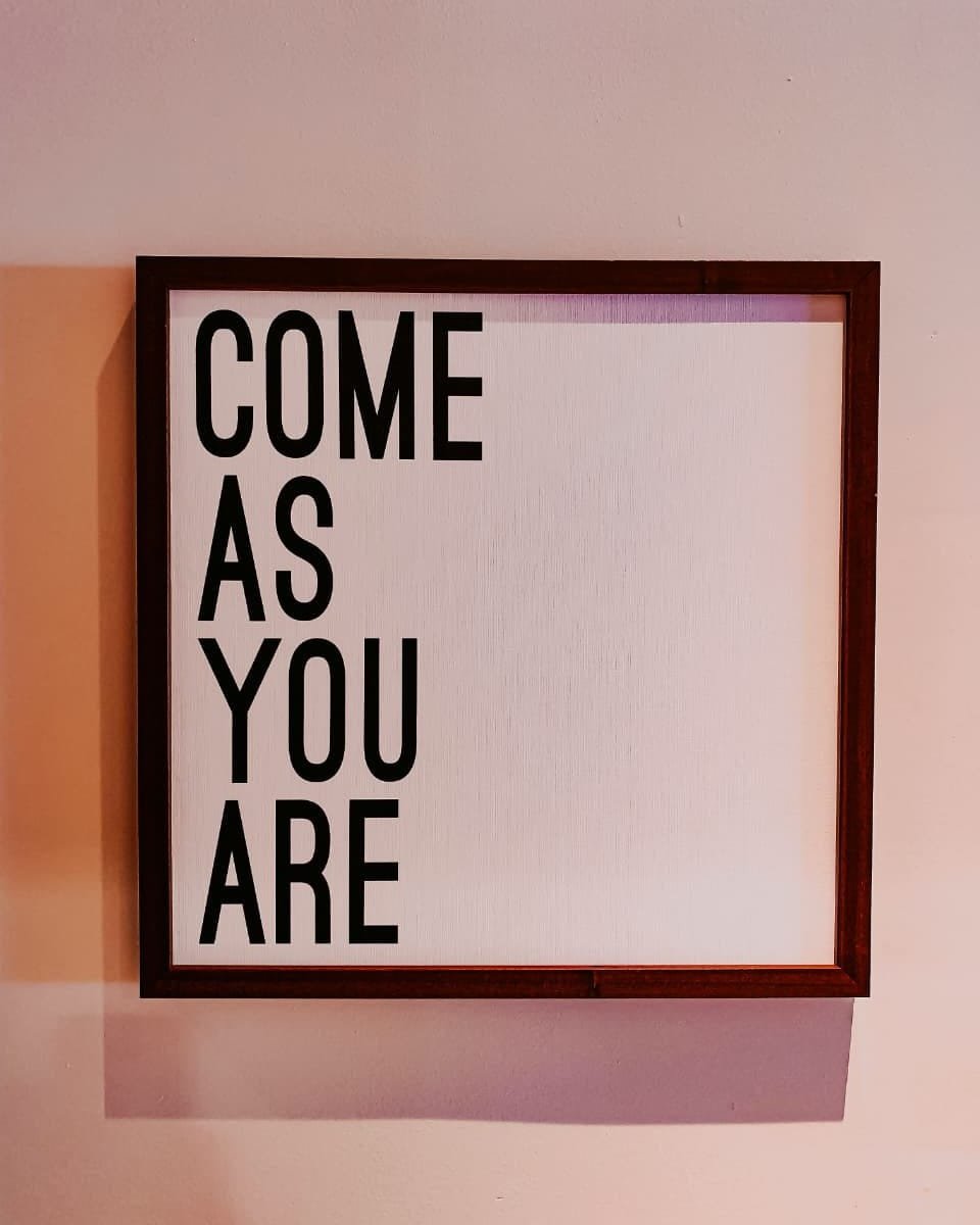 A framed print reading come as you are