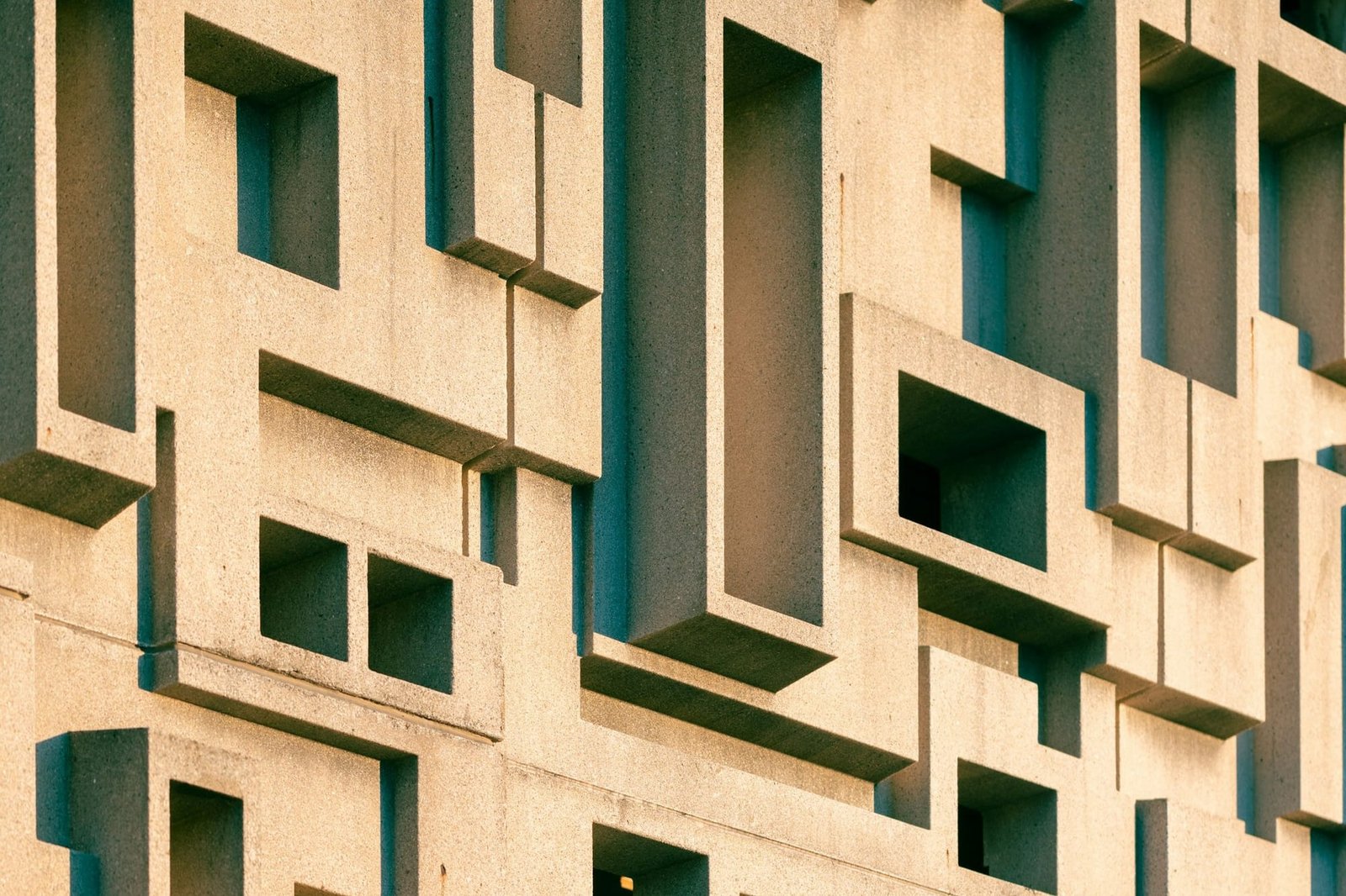 A deep-relief concrete facade, shaded openings cut into the structure itself